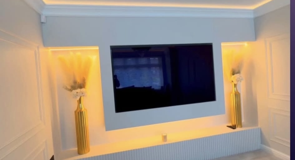 Completed feature media wall with warm lighting and panelled detailing