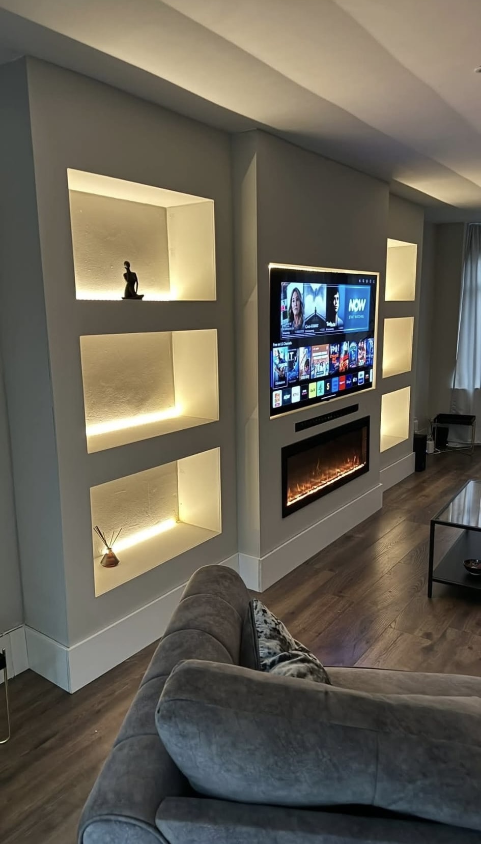 Contemporary media wall with illuminated shelving and fireplace